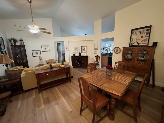 dining area featuring high vaulted ceiling, ceiling fan, and light wood-style flooring