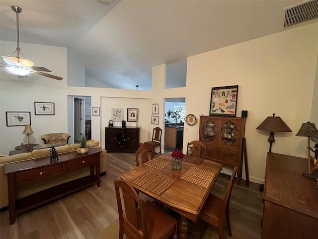 dining space with high vaulted ceiling, visible vents, ceiling fan, and wood finished floors