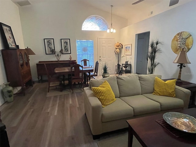 living room with high vaulted ceiling, wood finished floors, and ceiling fan with notable chandelier