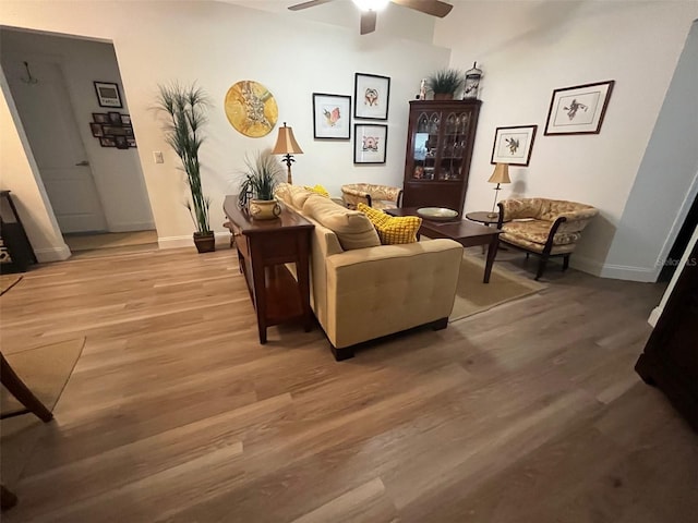 living area with light wood-style floors, baseboards, and a ceiling fan