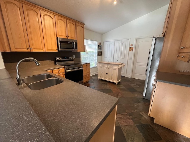 kitchen featuring lofted ceiling, appliances with stainless steel finishes, dark countertops, and a sink