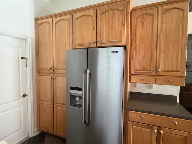 kitchen with dark countertops and stainless steel fridge with ice dispenser