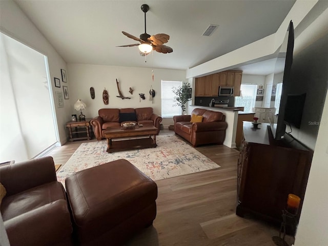 living area featuring plenty of natural light, visible vents, and wood finished floors