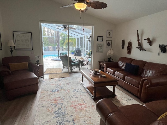 living area with ceiling fan, a sunroom, vaulted ceiling, and wood finished floors