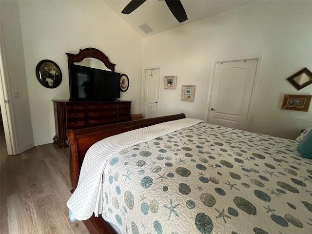 bedroom featuring lofted ceiling, ceiling fan, wood finished floors, visible vents, and baseboards