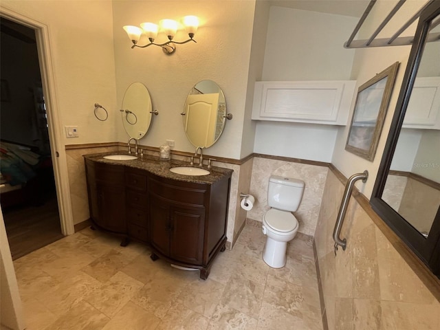 bathroom with wainscoting, a sink, toilet, and tile walls