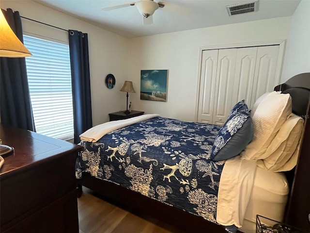 bedroom featuring ceiling fan, a closet, wood finished floors, and visible vents