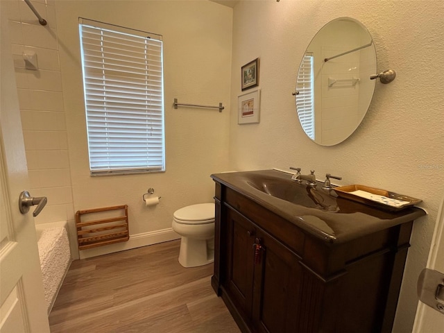 bathroom featuring toilet, wood finished floors, bathing tub / shower combination, vanity, and baseboards