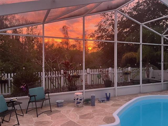 pool at dusk featuring a lanai, fence, a fenced in pool, and a patio