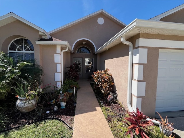 entrance to property featuring an attached garage and stucco siding