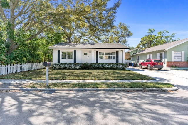 view of front of house featuring driveway, a front lawn, and fence