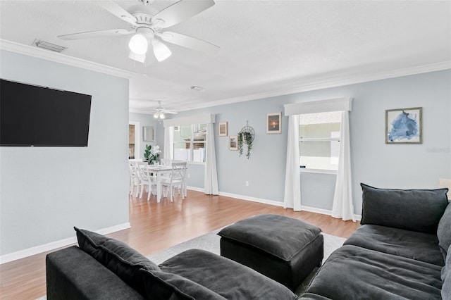 living area featuring visible vents, crown molding, ceiling fan, and wood finished floors