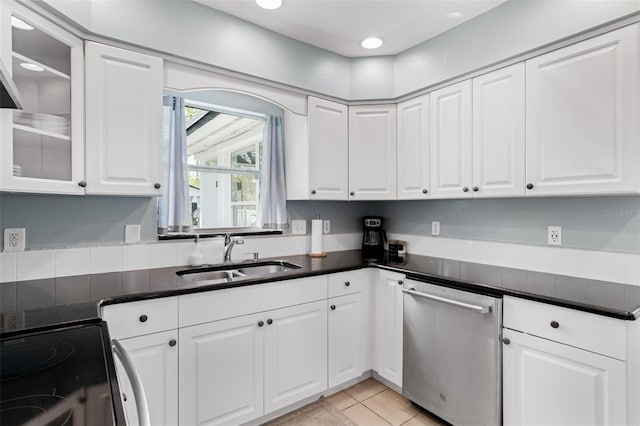 kitchen with stainless steel dishwasher, dark countertops, electric range oven, and a sink