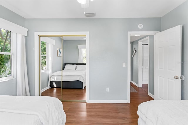 bedroom featuring multiple windows, wood finished floors, visible vents, and a closet