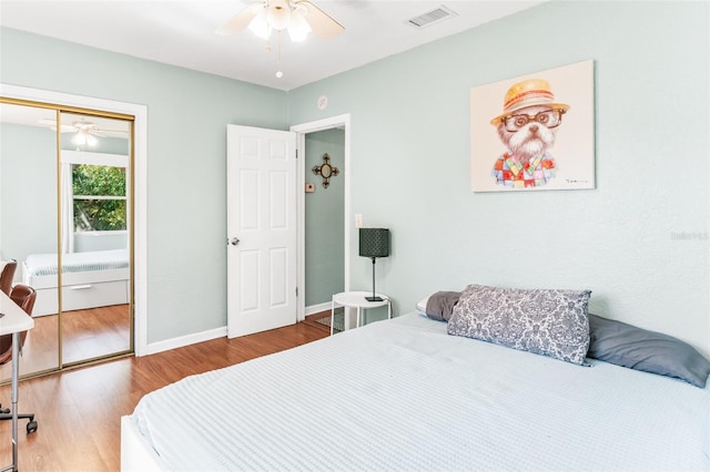 bedroom featuring visible vents, ceiling fan, baseboards, wood finished floors, and a closet