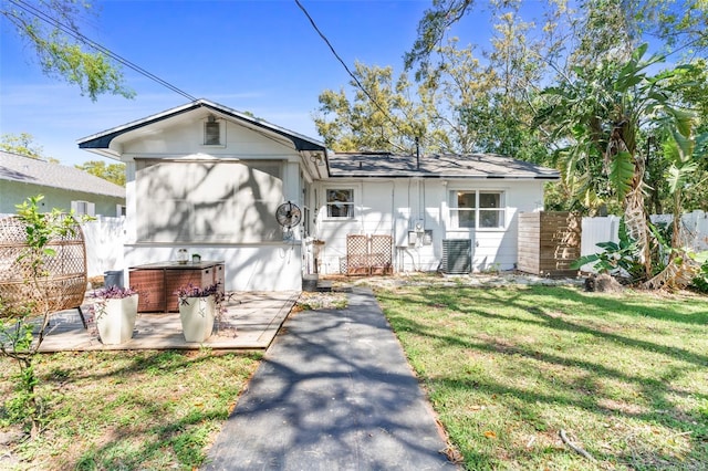 view of front of property with central air condition unit, a front yard, a jacuzzi, and fence