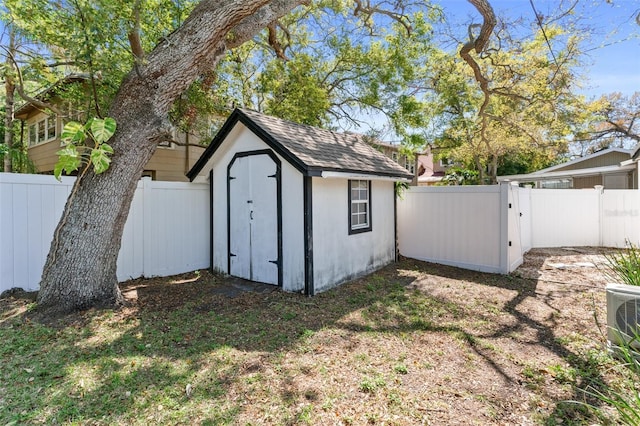 view of shed with cooling unit, a fenced backyard, and a gate