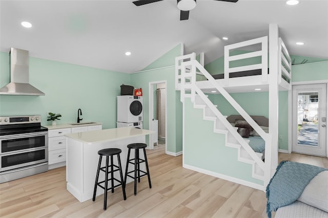 kitchen with double oven range, a breakfast bar area, washer / dryer, wall chimney exhaust hood, and a sink