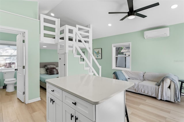 kitchen with a wall mounted air conditioner, a wealth of natural light, a ceiling fan, and white cabinetry