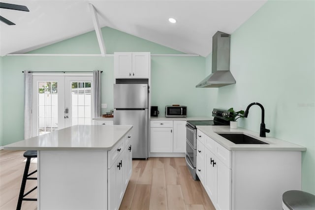 kitchen featuring wall chimney range hood, a kitchen bar, lofted ceiling, appliances with stainless steel finishes, and a sink