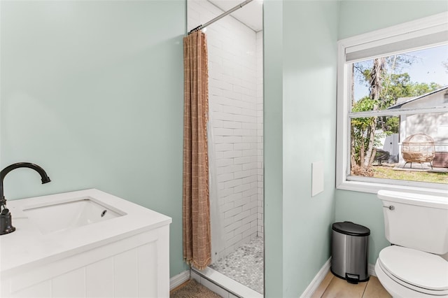 bathroom with a sink, baseboards, toilet, and a shower stall