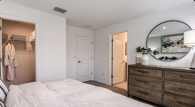 bedroom with light colored carpet, visible vents, and a textured ceiling