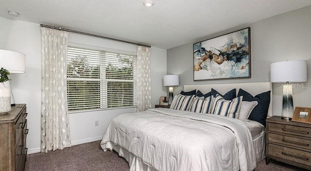 bedroom with dark carpet, a textured ceiling, and baseboards