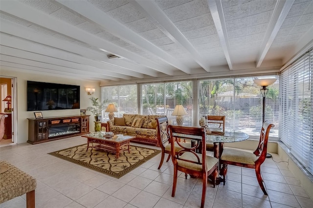 sunroom / solarium with a glass covered fireplace, a healthy amount of sunlight, and beamed ceiling