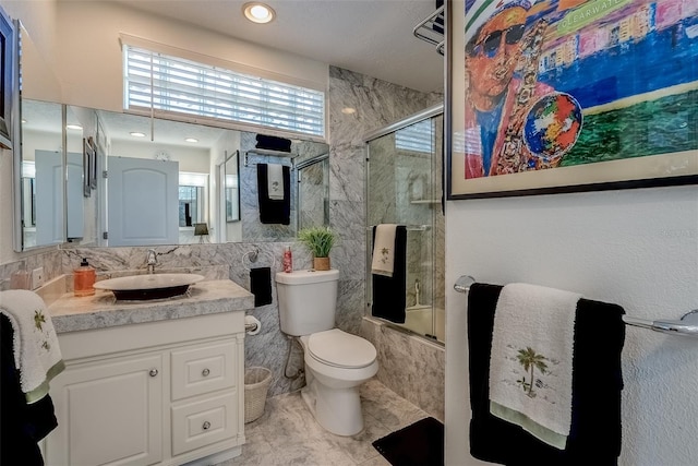 bathroom with toilet, shower / bath combination with glass door, tile walls, and vanity