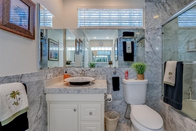 full bathroom with toilet, vanity, tile walls, and a healthy amount of sunlight