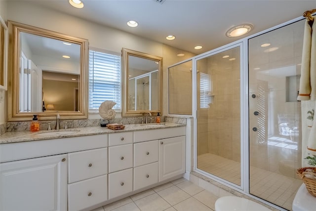 bathroom featuring double vanity, a stall shower, a sink, and tile patterned floors