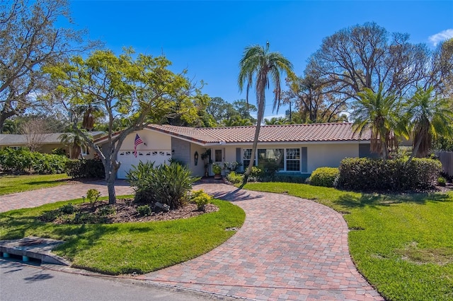 ranch-style house with a tiled roof, an attached garage, decorative driveway, a front yard, and stucco siding