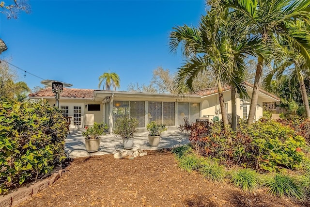 view of front of property featuring french doors, a tile roof, a patio, and stucco siding