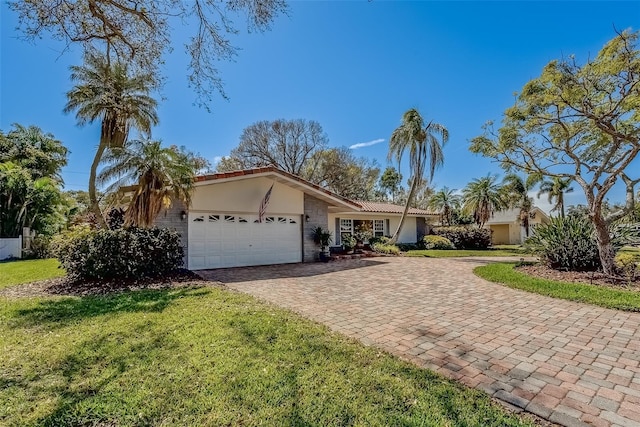 ranch-style house with a front lawn, decorative driveway, an attached garage, and stucco siding