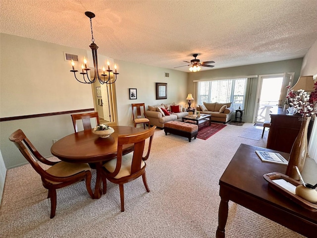 carpeted dining room featuring visible vents, a textured ceiling, and ceiling fan with notable chandelier