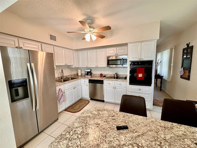 kitchen with visible vents, decorative backsplash, black appliances, white cabinetry, and a sink