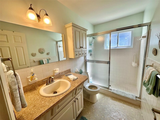 bathroom with vanity, a shower stall, tile walls, and tile patterned floors