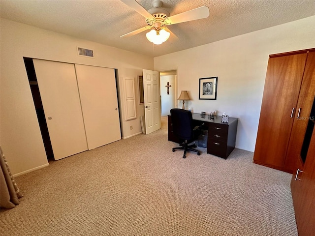 office featuring light colored carpet, visible vents, ceiling fan, and a textured ceiling