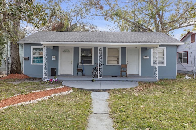 view of front of home featuring a porch, a front yard, a shingled roof, and stucco siding