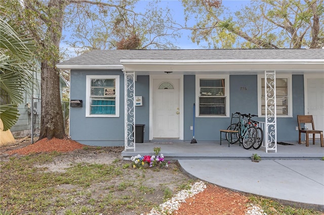 view of front of home featuring a porch, a shingled roof, and stucco siding