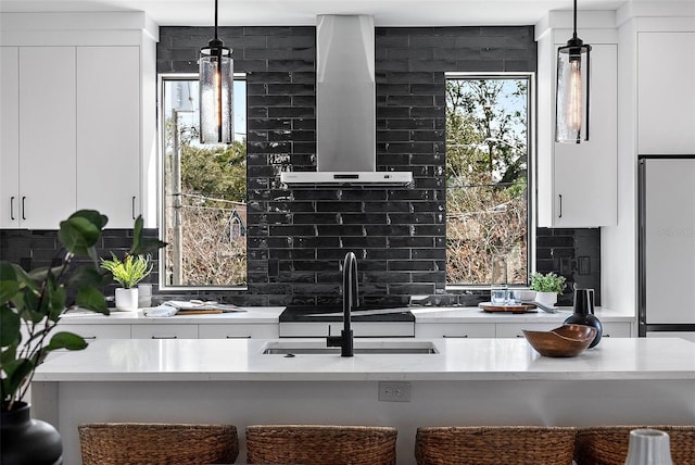 kitchen with exhaust hood, a kitchen bar, and white cabinetry