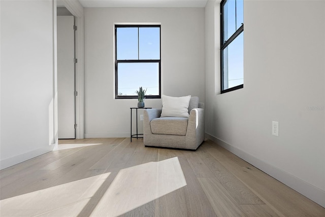 sitting room featuring light wood-type flooring, plenty of natural light, and baseboards