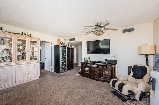 carpeted living room with a textured ceiling, ceiling fan, and visible vents