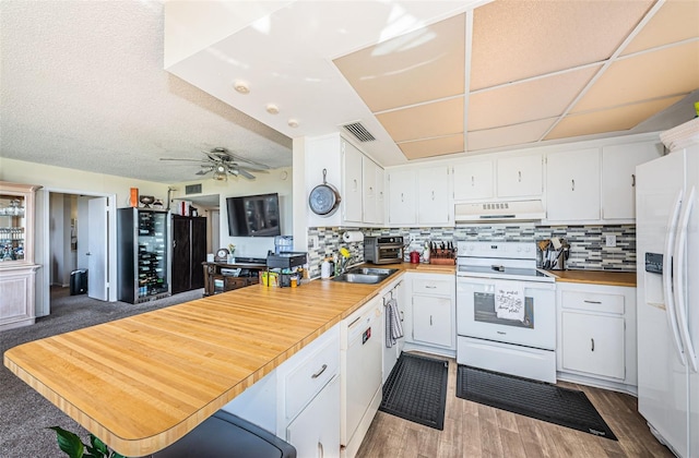 kitchen with visible vents, decorative backsplash, white appliances, a peninsula, and exhaust hood