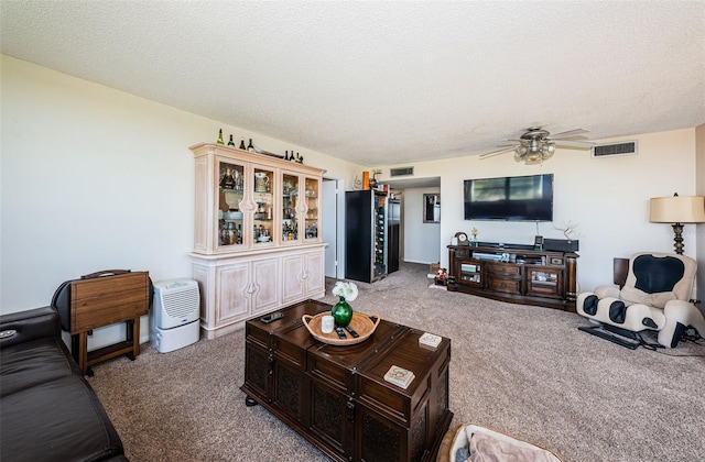 living room with visible vents, ceiling fan, a textured ceiling, and carpet flooring