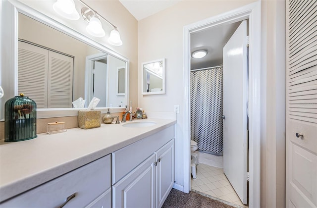 bathroom with a closet, vanity, toilet, and tile patterned floors