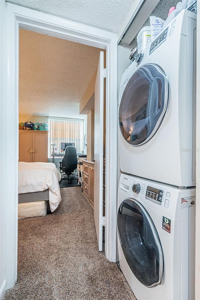 clothes washing area featuring stacked washer / drying machine, laundry area, a textured ceiling, and carpet