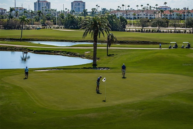 surrounding community with view of golf course, a yard, and a water view