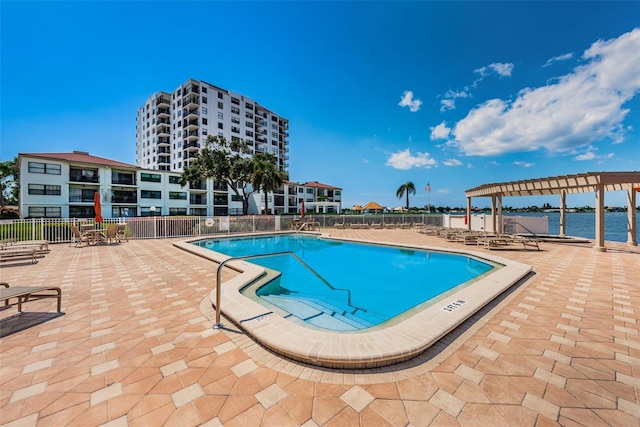 pool featuring a patio, a water view, fence, and a pergola