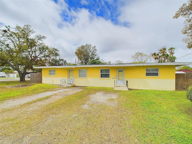 ranch-style home featuring entry steps, driveway, a front yard, and fence